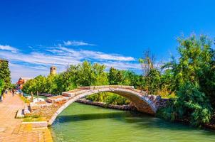 ponte do diabo de pedra através do canal de água na ilha de torcello foto