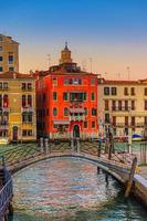 ponte sobre o canal de água estreito e palácios de edifícios de estilo barroco na via navegável do grande canal em veneza foto