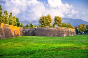 muralha defensiva da cidade de tijolos, gramado verde, árvores e colinas e montanhas da Toscana foto