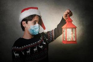feliz natal, garoto com máscara médica segurando uma lanterna velha foto