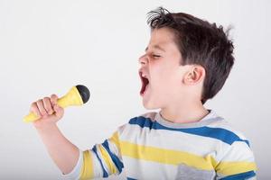menino cantando com um microfone foto