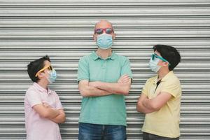 pai com seus filhos usando máscara médica e óculos de sol foto