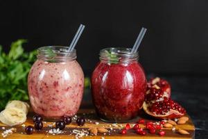 smoothies preparados na hora de banana com romã e banana com amora em garrafa. dieta, estilo de vida saudável foto