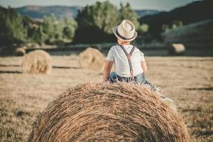 criança pensativa no campo de palha foto