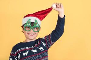 criança usando chapéu de papai noel de natal e óculos engraçados foto