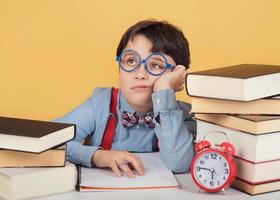 menino triste e pensativo com livros em uma mesa foto