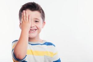 criança sorridente cobrindo o olho foto