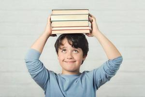 criança feliz e sorridente com livros na cabeça foto