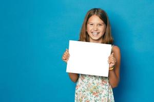 linda menina sorridente com dentes brancos, segurando nas mãos o espaço em branco da cópia em branco para o anúncio foto