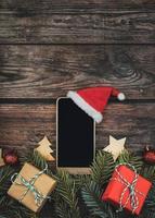 fundo do conceito de natal smartphone com chapéu de papai noel e galhos de árvore de natal foto