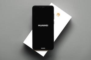 logotipo da huawei na tela preta do smartphone em cima de sua caixa branca foto