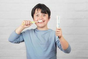 criança feliz, limpando os dentes pela escova de dentes foto