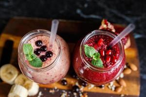 smoothies preparados na hora de banana com romã e banana com amora em garrafa. dieta, estilo de vida saudável foto