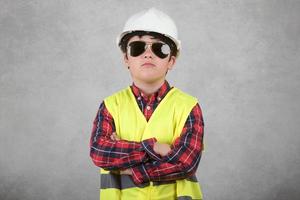 trabalhador da construção civil criança no capacete branco e óculos de sol foto