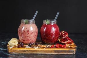 smoothies preparados na hora de banana com romã e banana com amora em garrafa. dieta, estilo de vida saudável foto