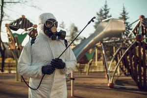 limpeza e desinfecção no playground no complexo da cidade em meio às equipes de epidemia de coronavírus para esforços de desinfecção prevenção de infecções e controle de traje de proteção e máscara epidêmica foto