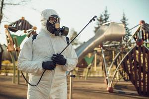 limpeza e desinfecção no playground no complexo da cidade em meio às equipes de epidemia de coronavírus para esforços de desinfecção prevenção de infecções e controle de traje de proteção e máscara epidêmica foto