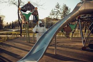 limpeza e desinfecção no playground no complexo da cidade em meio às equipes de epidemia de coronavírus para esforços de desinfecção prevenção de infecções e controle de traje de proteção e máscara epidêmica foto