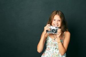 linda garota sorridente com dentes brancos, segurando uma câmera instantânea foto