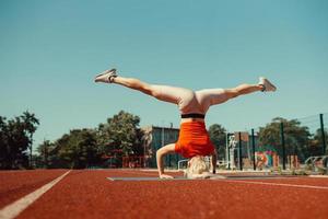 jovem loira aprende a se equilibrar em uma parada de cabeça e de mão foto