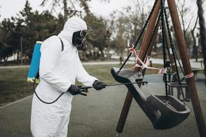 limpeza e desinfecção no playground no complexo da cidade em meio às equipes de epidemia de coronavírus para esforços de desinfecção prevenção de infecções e controle de traje de proteção e máscara epidêmica foto