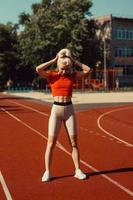 garota fazendo um aquecimento antes de exercícios esportivos no estádio da escola foto