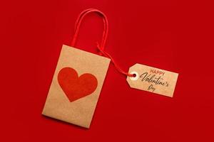 vista superior da sacola de compras com um coração vermelho e marca de venda marrom com texto feliz dia dos namorados. conceito de celebração do dia dos namorados foto
