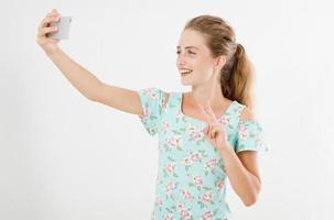 linda mulher sexy de vestido tirando uma selfie isolada no fundo branco, espaço de cópia, celular de mão feminina foto