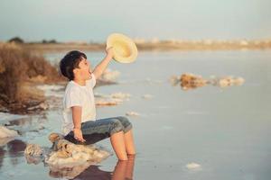 criança feliz com chapéu na praia foto
