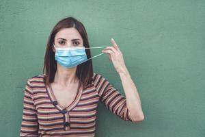 mulher usando máscara médica segurando uma máscara médica protetora foto