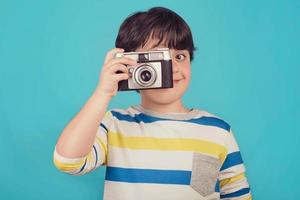 menino sorridente com câmera fotográfica foto