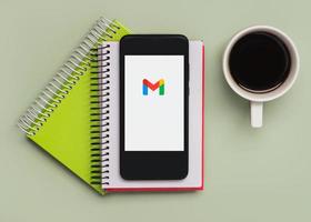 logotipo do gmail na tela preta do smartphone com notebooks e café foto