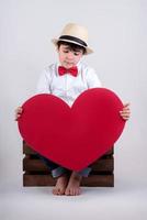 criança pensativa com um coração vermelho foto