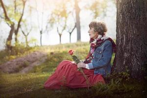 pensativa mulher sênior sentada na grama foto