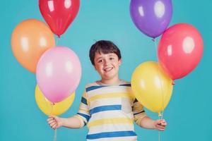 menino feliz e sorridente com balões coloridos foto