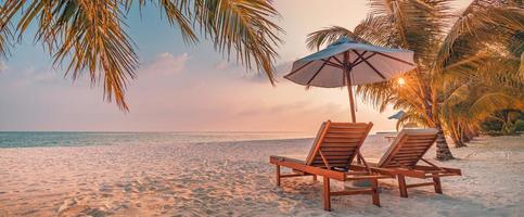 incrível praia romântica. cadeiras na praia de areia perto do mar. conceito de férias de férias de verão para turismo. paisagem de ilha tropical. cenário tranquilo da costa, relaxe o horizonte à beira-mar, folhas de palmeira foto