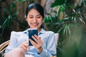 bela jovem mulher asiática usando telefone no jardim foto