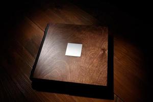 livro de fotos em uma capa de madeira em uma mesa de madeira. luz dura