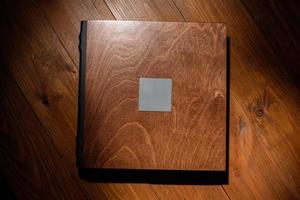 livro de fotos em uma capa de madeira em uma mesa de madeira. luz dura