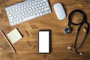 telefone celular, teclado, mouse e instrumento médico em uma mesa foto