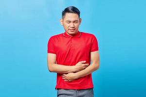 retrato de jovem asiático bonito doente com problemas de saúde de dor de estômago diarréia desconforto, constipação no intestino isolado em fundo azul foto