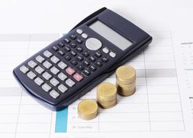 calculadora e pilha de moedas em fundos de calendário para o conceito de finanças empresariais foto
