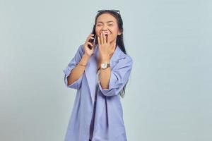 retrato de uma jovem asiática alegre falando no celular com as mãos cobrindo a boca isolada no fundo branco foto