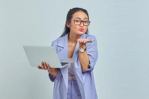 retrato de uma jovem asiática alegre em pé usando laptop e enviando beijo aéreo isolado sobre fundo branco foto