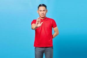 retrato de jovem asiático irritado cruzando as mãos faz gesto de pare, demonstra rejeição isolado sobre fundo azul foto