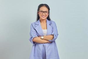 retrato de uma jovem asiática sorridente em pé com os braços cruzados, olhando para a câmera isolada no fundo branco foto