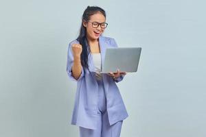 retrato de uma jovem asiática animada em pé segurando o laptop e comemorando a sorte para o novo emprego isolado no fundo branco foto