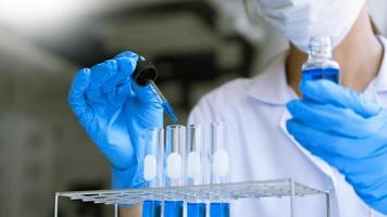 cientistas pesquisando em laboratório em jaleco branco, analisando luvas, olhando para amostra de tubos de ensaio, conceito de biotecnologia foto