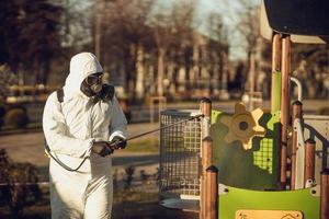 limpeza e desinfecção no playground no complexo da cidade em meio às equipes de epidemia de coronavírus para esforços de desinfecção prevenção de infecções e controle de traje de proteção e máscara epidêmica foto