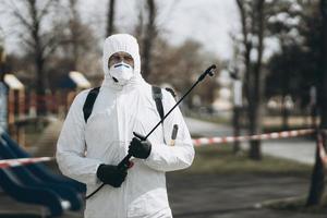 limpeza e desinfecção no complexo da cidade em meio à epidemia de coronavírus equipes profissionais para esforços de desinfecção prevenção de infecções e controle de traje e máscara de proteção epidêmica foto